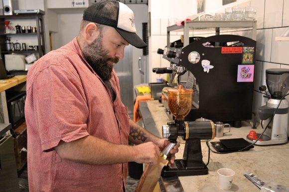 Charlie, dueño de Café Zavalía, muele granos en molinillo pequeño