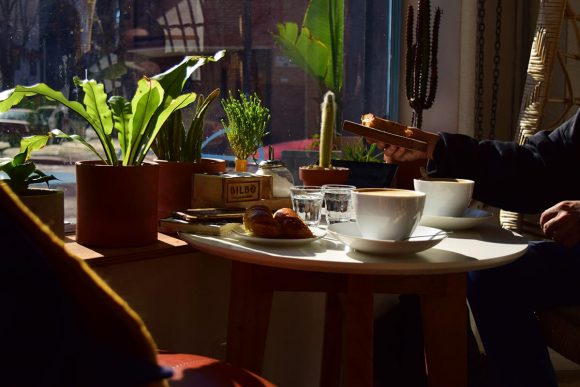 Una de las mesas de Bilbo junto a la ventana con un capuccino